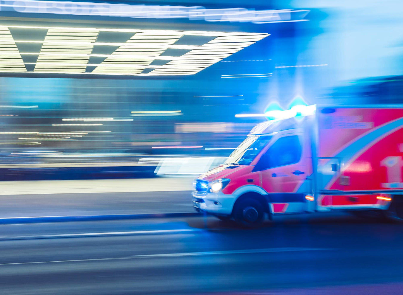An ambulance moving fast with lights on against a blurred background