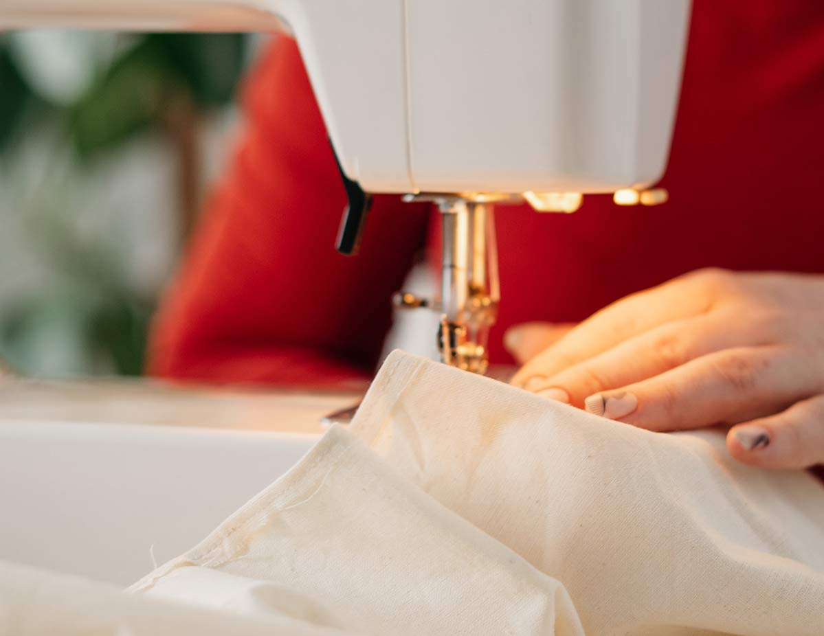 Hand pushing fabric through a sewing machine
